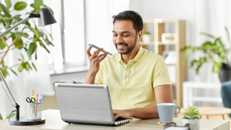 man recording voice on smartphone at home office