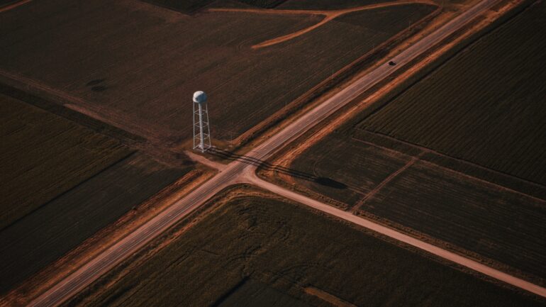 Beautiful aerial shot of narrow roads intersection in the countryside with a white tower