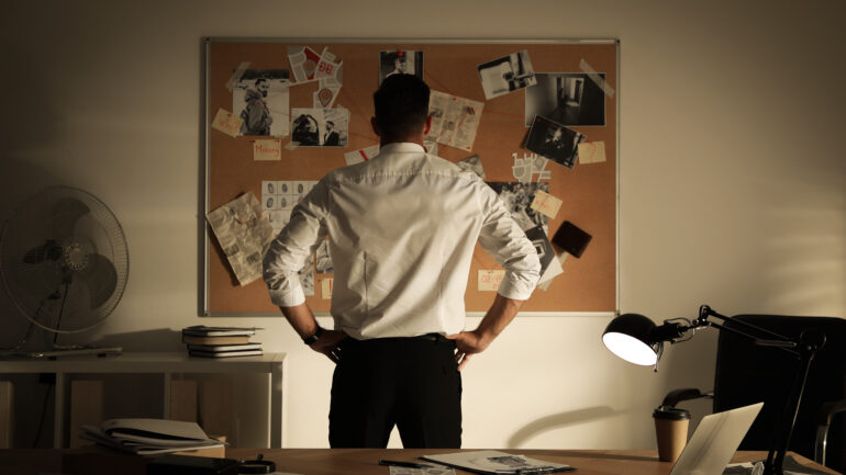 Detective looking at evidence board in office